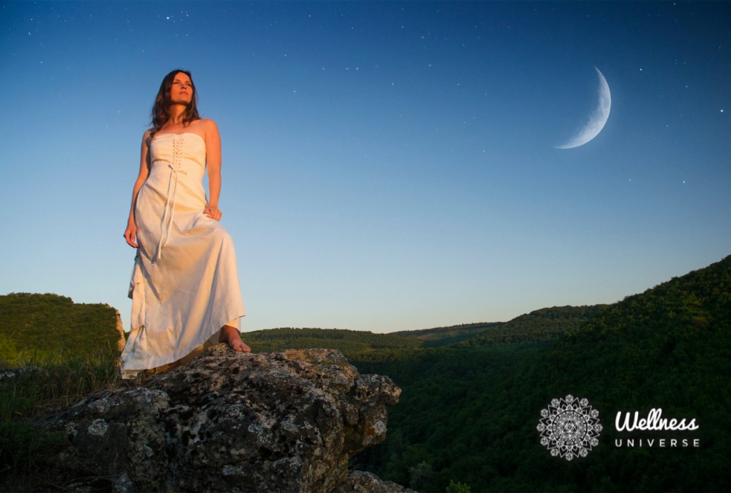 Woman standing on a rock with the moon in the background